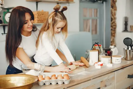 enfant et sa maman qui préparent un gâteau d'anniversaire ensemble en cuisine